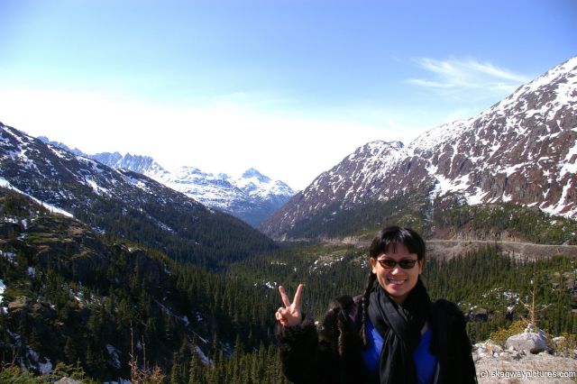 Joann gives the peace sign with Skagway mountains in the background.jpg